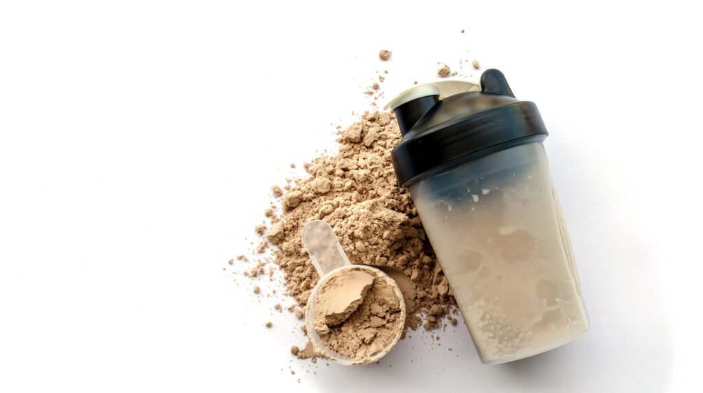 A protein shaker bottle placed on a surface with protein powder scattered around it, ready for mixing. The image represents the convenience and versatility of protein supplements.