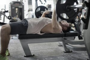 Man performing a barbell bench press at the gym as part of his 5 best chest workouts for building strength and muscle.